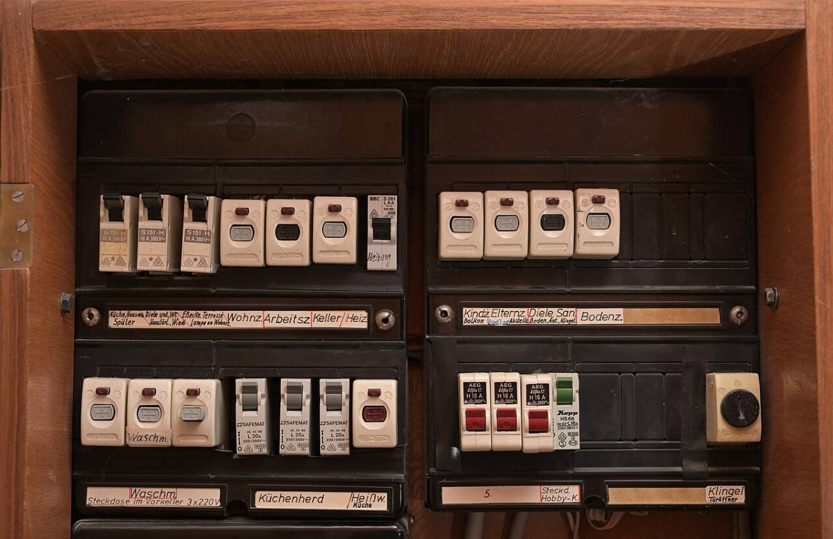 Alter Sicherungskasten aus den 1960er-Jahren mit handbeschrifteten Sicherungen und offener Holztür